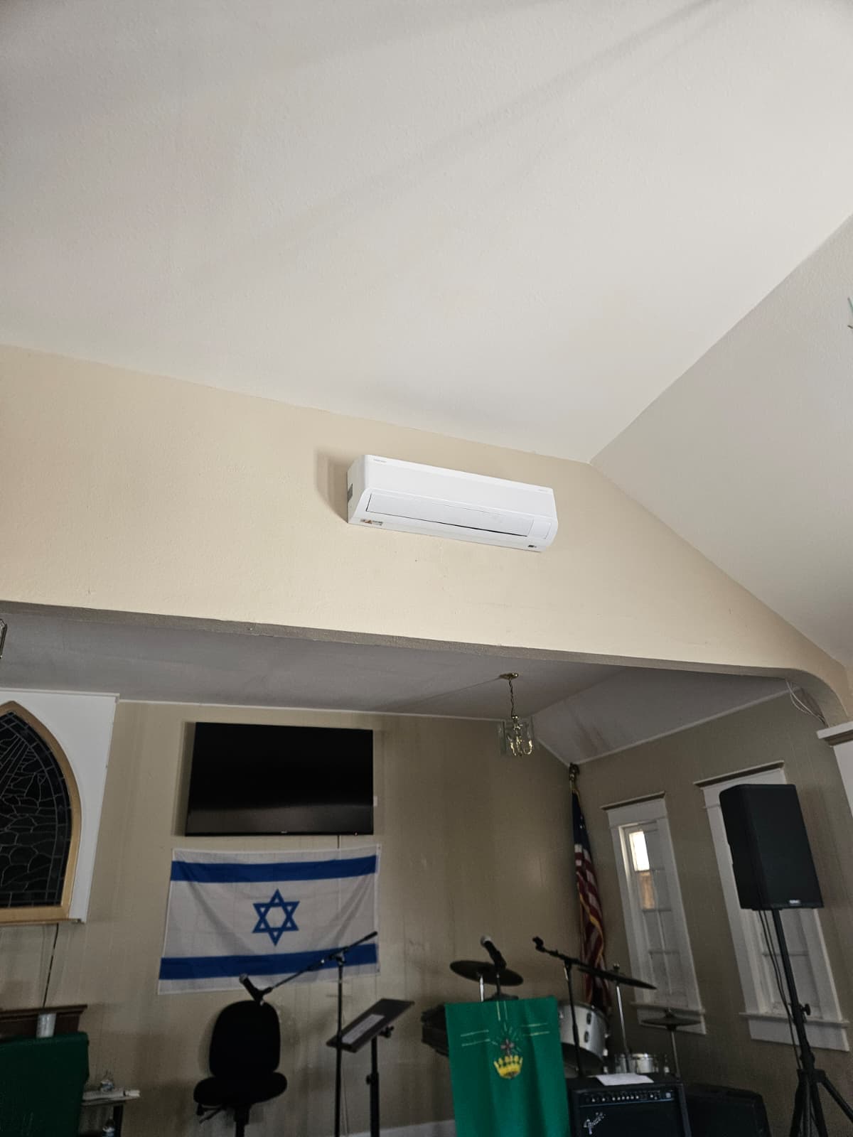 Ductless mini-split head mounted near the ceiling of a large meeting hall
