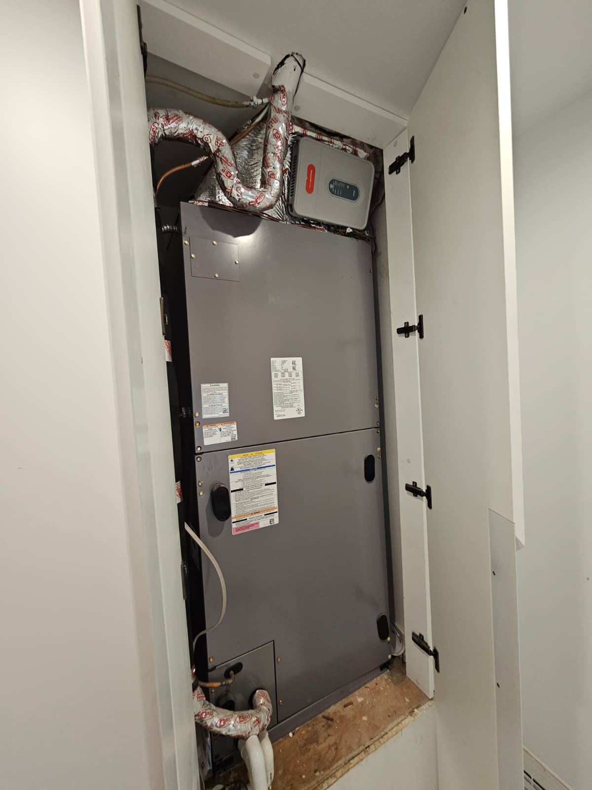 Vertical air handler installed inside an indoor closet with insulated flex duct