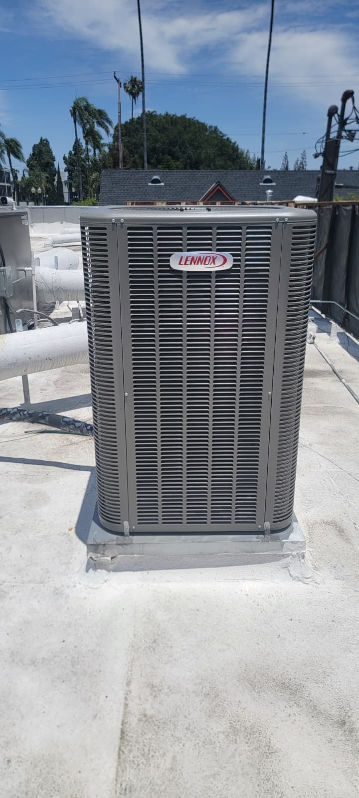 Unidad condensadora exterior Lennox sobre una base de azotea junto a las líneas de refrigerante